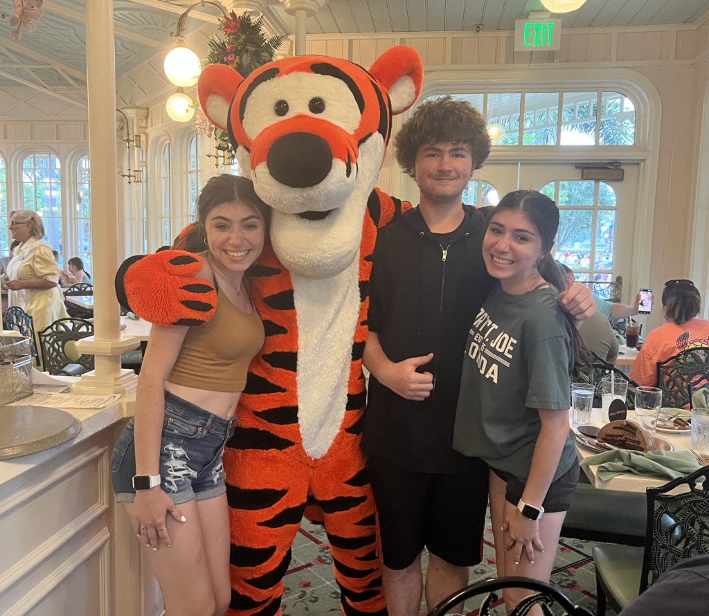 Tigger with three teenaged children smiling and posing for the camers